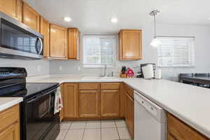Kitchen featuring black range with electric stovetop, light countertops, stainless steel microwave, white dishwasher, and a textured ceiling