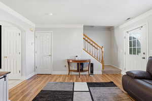 Foyer entrance featuring arched walkways, light wood-style flooring, ornamental molding, and a textured ceiling