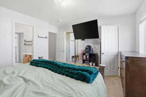 Bedroom with light colored carpet and connected bathroom