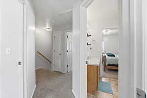 Hall featuring light colored carpet, an upstairs landing, and a textured ceiling