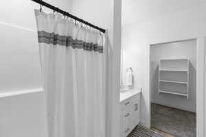 Bathroom with vanity, a spacious closet, a shower with shower curtain, and carpet