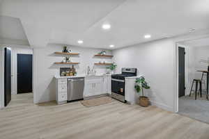 Kitchen featuring white cabinetry, stainless steel appliances, light wood-style flooring, open shelves, and recessed lighting