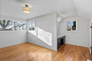 Bonus room with lofted ceiling, light wood-style flooring, and built in desk