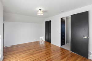 Unfurnished bedroom featuring lofted ceiling, light wood-style floors, and a closet