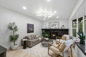 Living room featuring light wood-type flooring, a high end fireplace, and recessed lighting