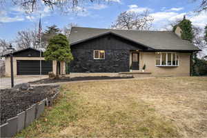 Mid-century home with roof with shingles, a garage, a front yard, a chimney, and concrete driveway