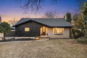 View of front of house featuring roof with shingles, a chimney, and brick siding