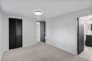 Unfurnished bedroom featuring light carpet, connected bathroom, and a closet