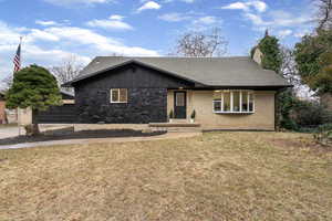 View of front facade featuring a shingled roof, a front lawn, brick siding, a garage, and a chimney
