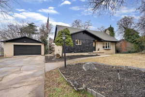 Mid-century inspired home with a garage, an outdoor structure, a chimney, and board and batten siding