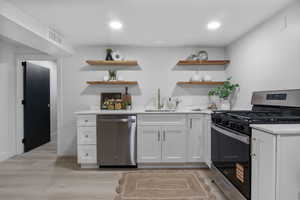 Kitchen with white cabinetry, open shelves, stainless steel appliances, light wood finished floors, and recessed lighting