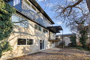 Back of house featuring a balcony, a patio area, and brick siding