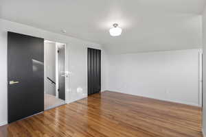 Unfurnished bedroom with vaulted ceiling and light wood-type flooring
