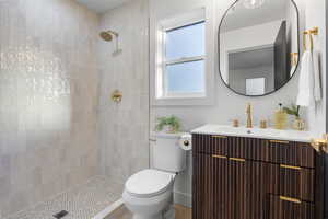 Full bathroom featuring vanity, a tile shower, and wood finished floors