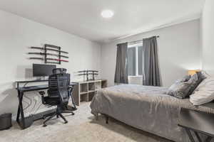 Bedroom with light colored carpet and a desk