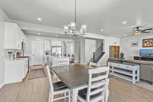 Dining space featuring light wood-style flooring, suspended lighting, and ceiling fan