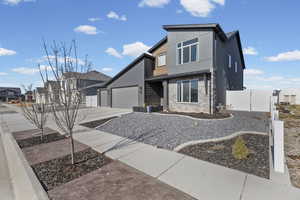 Modern home featuring stone siding, driveway, a garage, and a residential view