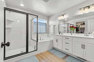 Bathroom with a stall shower, double vanity, light wood-style floors, and a bath