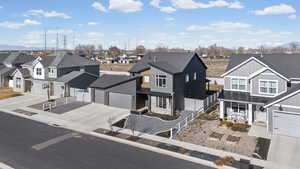 View of front of home with a residential view, concrete driveway, an attached garage, and stone siding