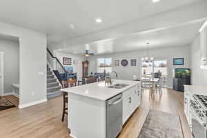 Kitchen featuring white cabinets, open floor plan, a breakfast bar, stainless steel appliances, and light wood-style flooring