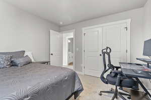 Bedroom with a desk, light colored carpet, and a closet
