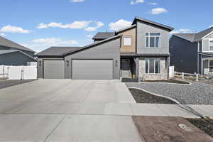 Contemporary house, stone siding, an attached garage, driveway, and a gate