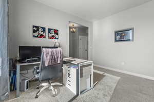 Carpeted home office with suspended lighting and baseboards