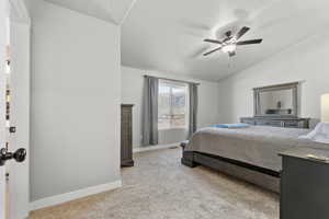 Bedroom with light colored carpet, lofted ceiling, and ceiling fan