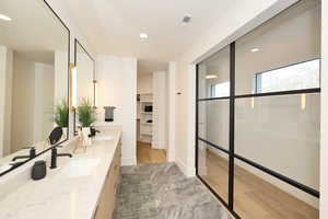 Full bathroom featuring double vanity, light wood-style flooring, a walk in closet, recessed lighting, and a walk in shower