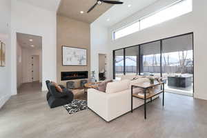 Living area featuring a fireplace, recessed lighting, a ceiling fan, and a high ceiling