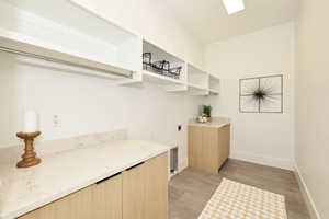 Laundry room with electric dryer hookup, concrete flooring, and cabinet space
