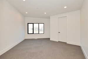 Empty room with light carpet and recessed lighting