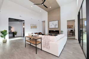 Living room featuring a high ceiling, a ceiling fan, a fireplace, and concrete floors