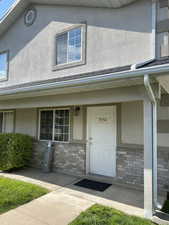 Doorway to property featuring stone siding and stucco siding