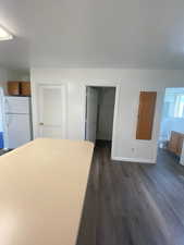 Kitchen with freestanding refrigerator, dark wood-style flooring, and light countertops