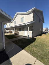 View of side of property with a yard, stucco siding, and covered porch