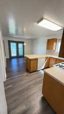Kitchen with a peninsula, wood finish cabinets, light countertops, dark wood-style flooring, and a textured ceiling
