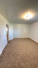 Spare room with a textured ceiling and dark colored carpet