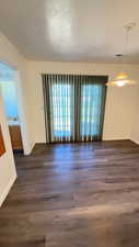 Spare room featuring dark wood-style flooring and baseboards