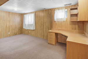 Family room featuring built in study area, light carpet, and wooden walls