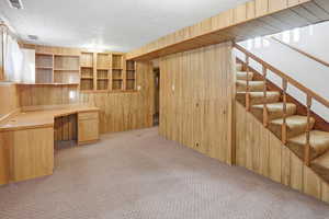 Family room featuring wood walls, built in desk, and light carpet