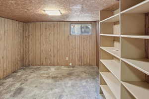 Basement featuring wood walls and cement floor.