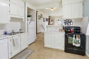 Kitchen with white appliances, white cabinets, light countertops, and a peninsula