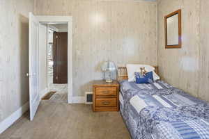 Carpeted bedroom with baseboards and light wood paneling.