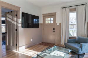 Foyer with a wainscoted wall, wood finished floors, plenty of natural light, and wooden walls