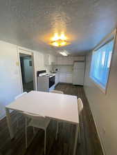 Kitchen with light countertops, white appliances, dark wood-style floors, a textured ceiling, and white cabinetry