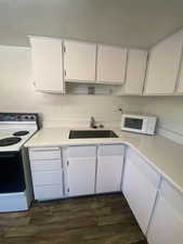 Kitchen with white cabinets, white appliances, and light countertops