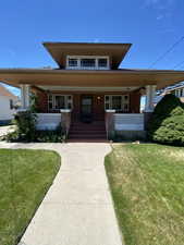 View of front of home featuring brick siding, covered porch, and a front lawn