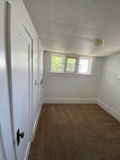 Spare room with dark carpet and baseboards