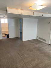 Below grade area with dark carpet and a drop ceiling